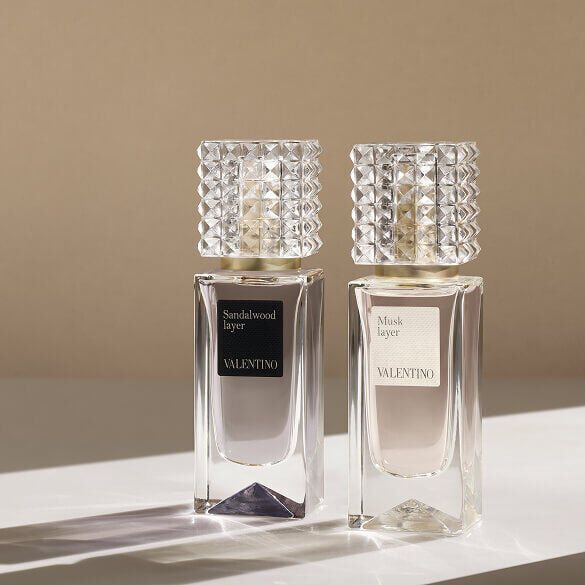 Due flaconi di profumo Valentino, etichettati Sandalwood Layer e Musk Layer, esposti su una superficie chiara