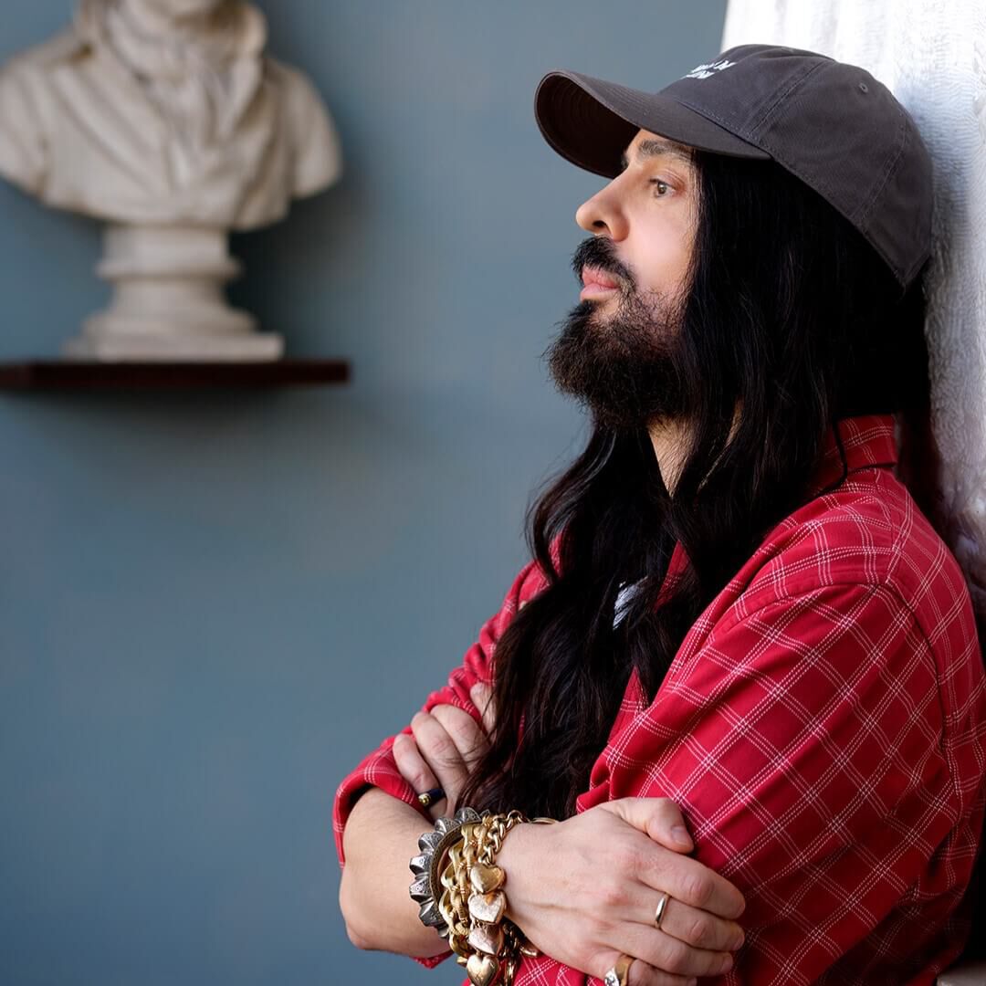 Alessandro Michele, creative director of Valentino, appoggiato al muro.